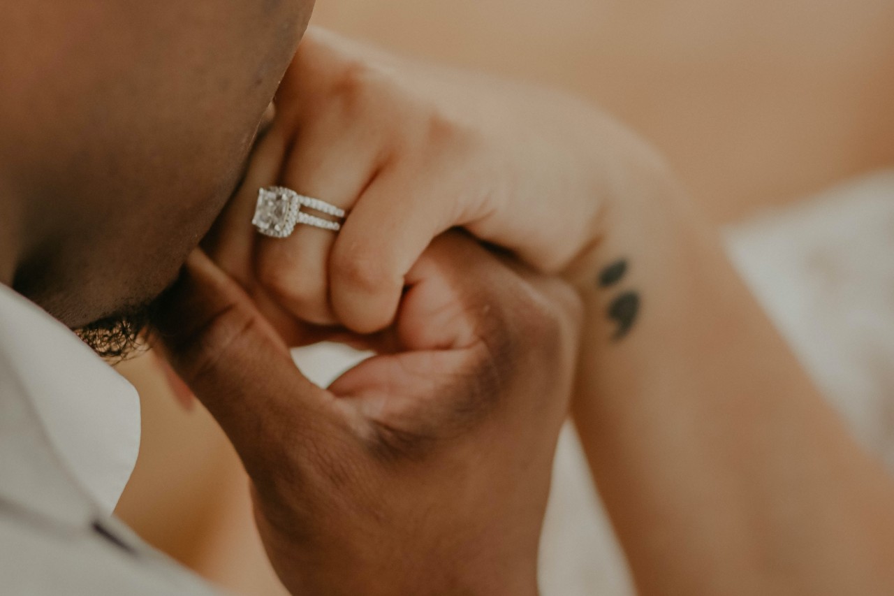 a man kissing his bride’s hand who is wearing a white gold engagement ring