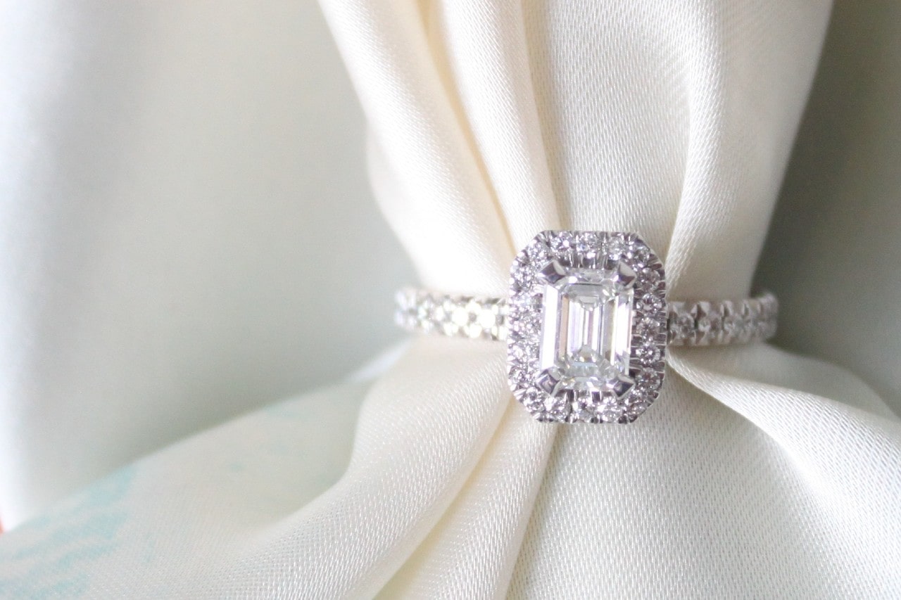 a white gold emerald cut engagement ring on a piece of white fabric