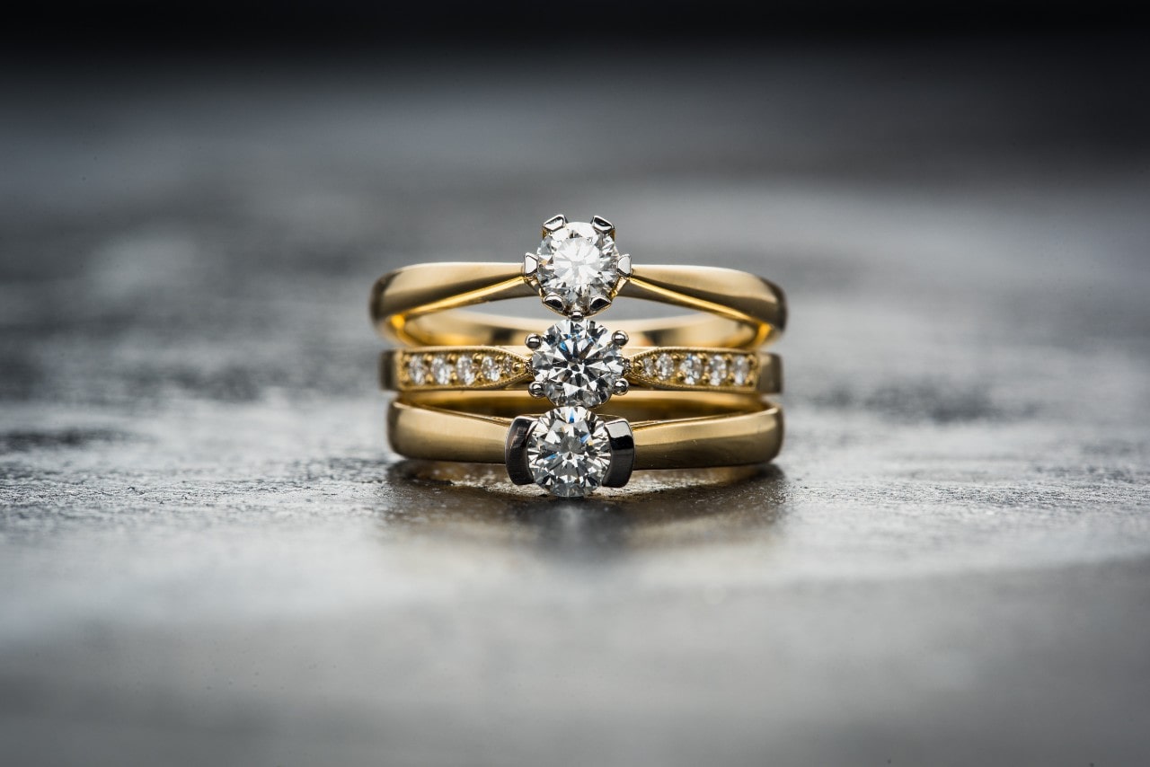 A trio of round-cut rings sitting on top of each other against a grey backdrop.