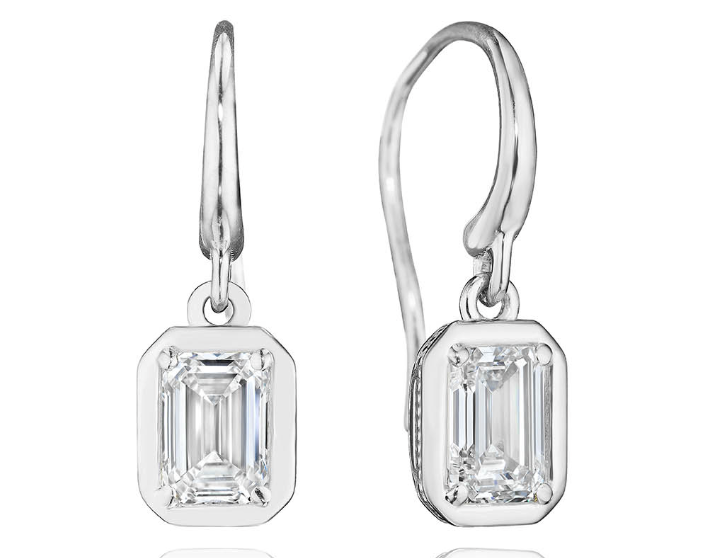 A white gold bezel set emerald cut diamond drop earrings.