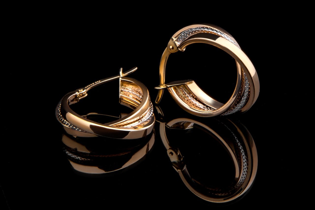 A pair of twisted yellow gold diamond huggies against a black background A pair of twisted yellow gold diamond huggies against a black background
