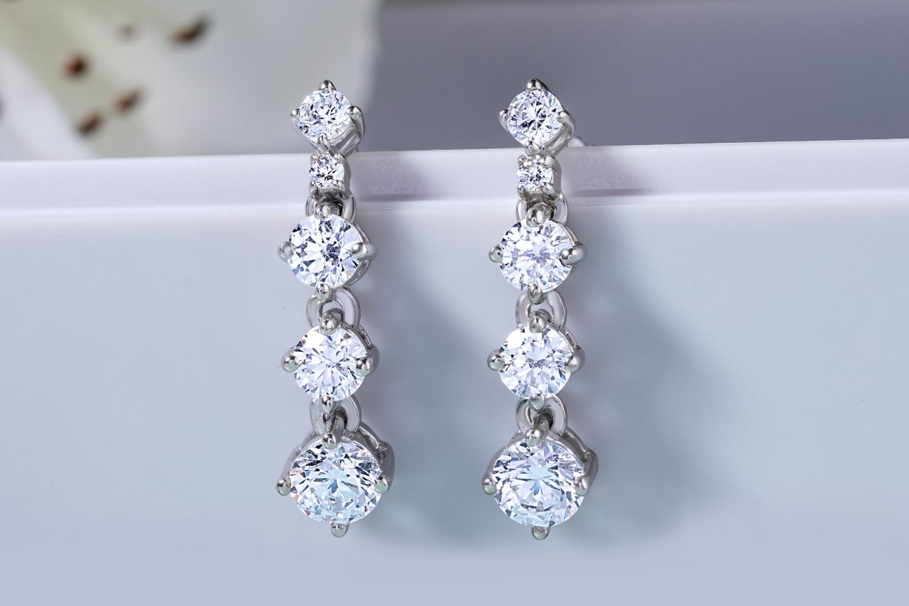 A pair of silver, four-tiered diamond earrings featuring round-cut diamonds