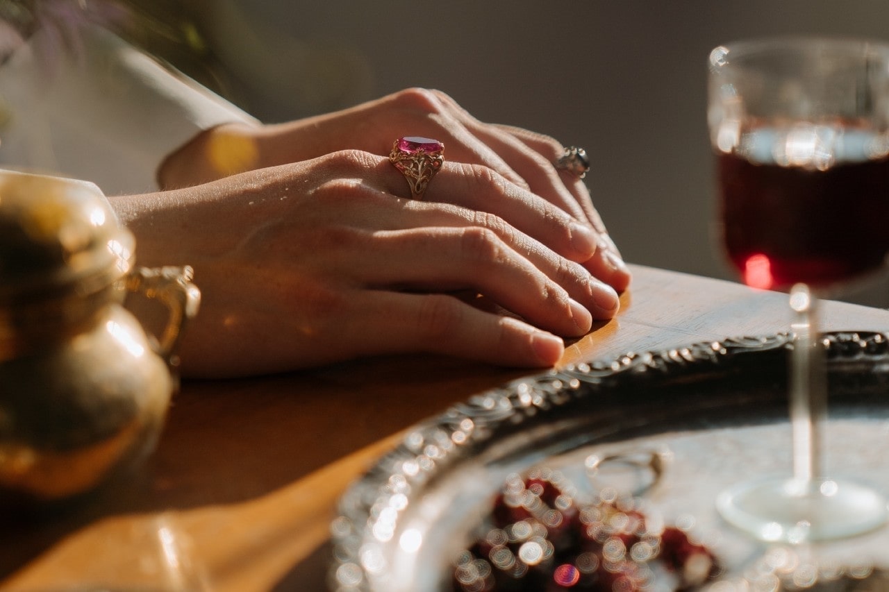 A lady's hand resting on a table and wearing fashion rings