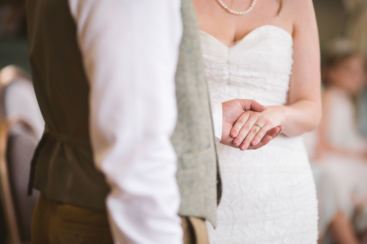 A husband holds his wife's hand to show off her wedding band