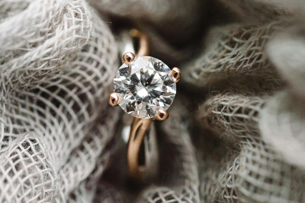 A rose gold diamond solitaire engagement ring inside the grey fabric