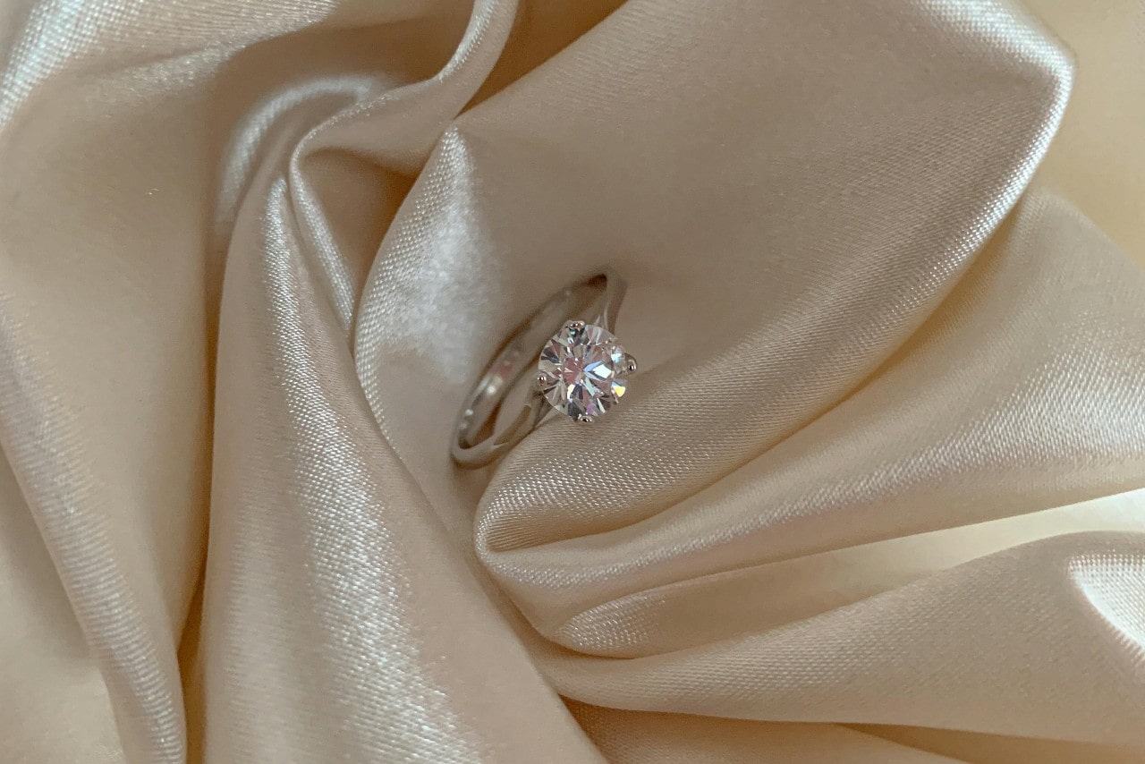 A white gold diamond engagement ring in the atlas white fabric