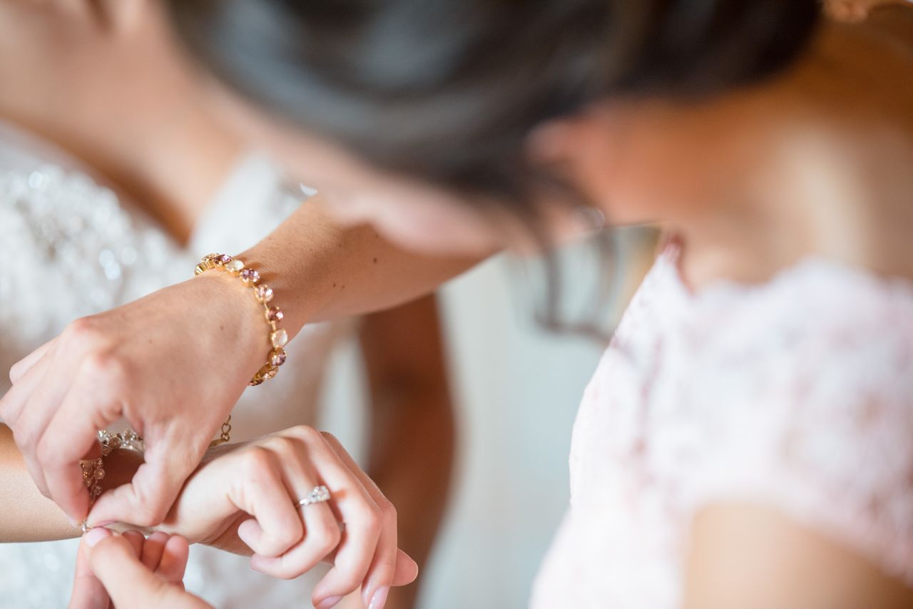 A woman wearing a gemstone bracelet fastens her friend's bracelet