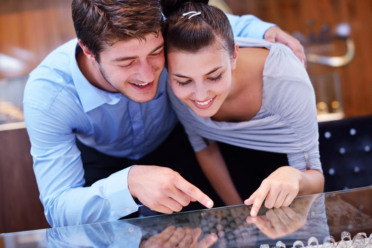 A couple looking at a display of rings in a jewellery store A couple looking at a display of rings in a jewellery store