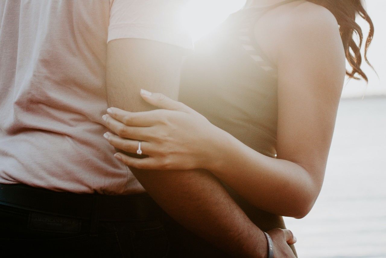 A man and woman wearing jewellery and embracing in the sunshine