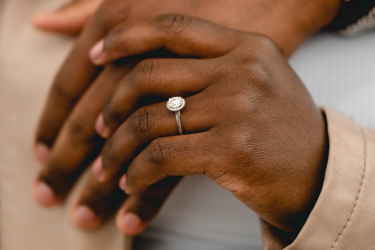 A closeup of an oval cut halo engagement ring on a woman’s hand.