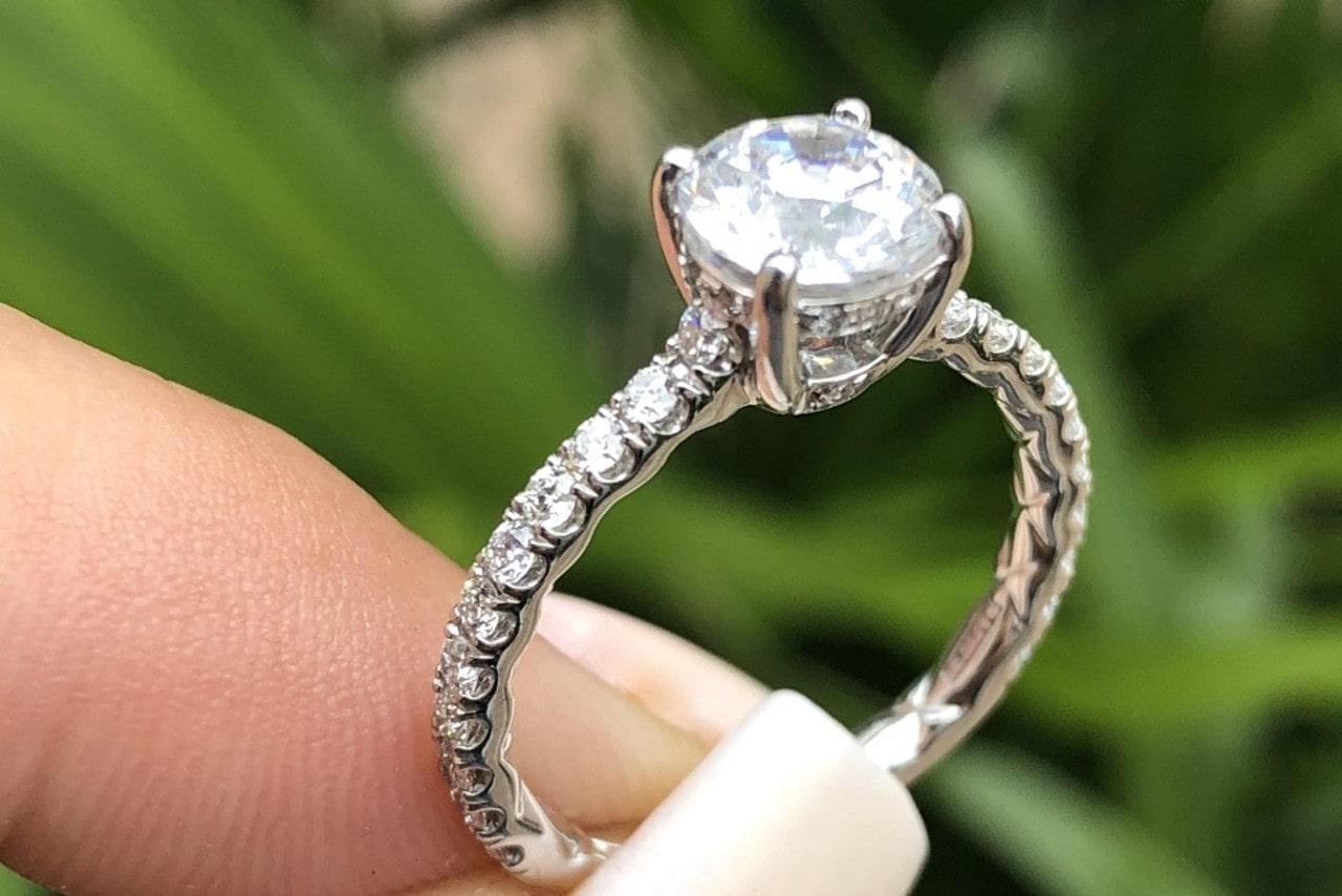 side stone engagement ring held between two fingers