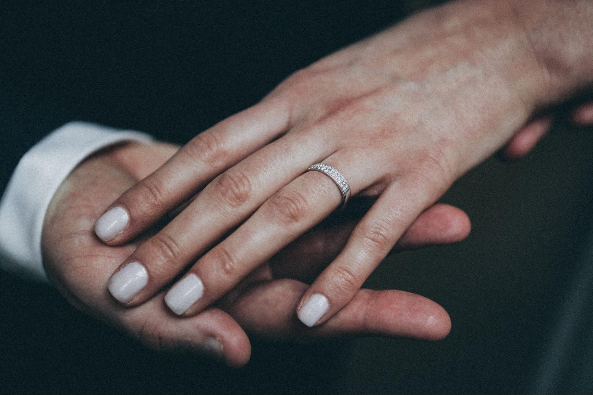 A woman rests her hand on her husband’s to show off her diamond wedding band