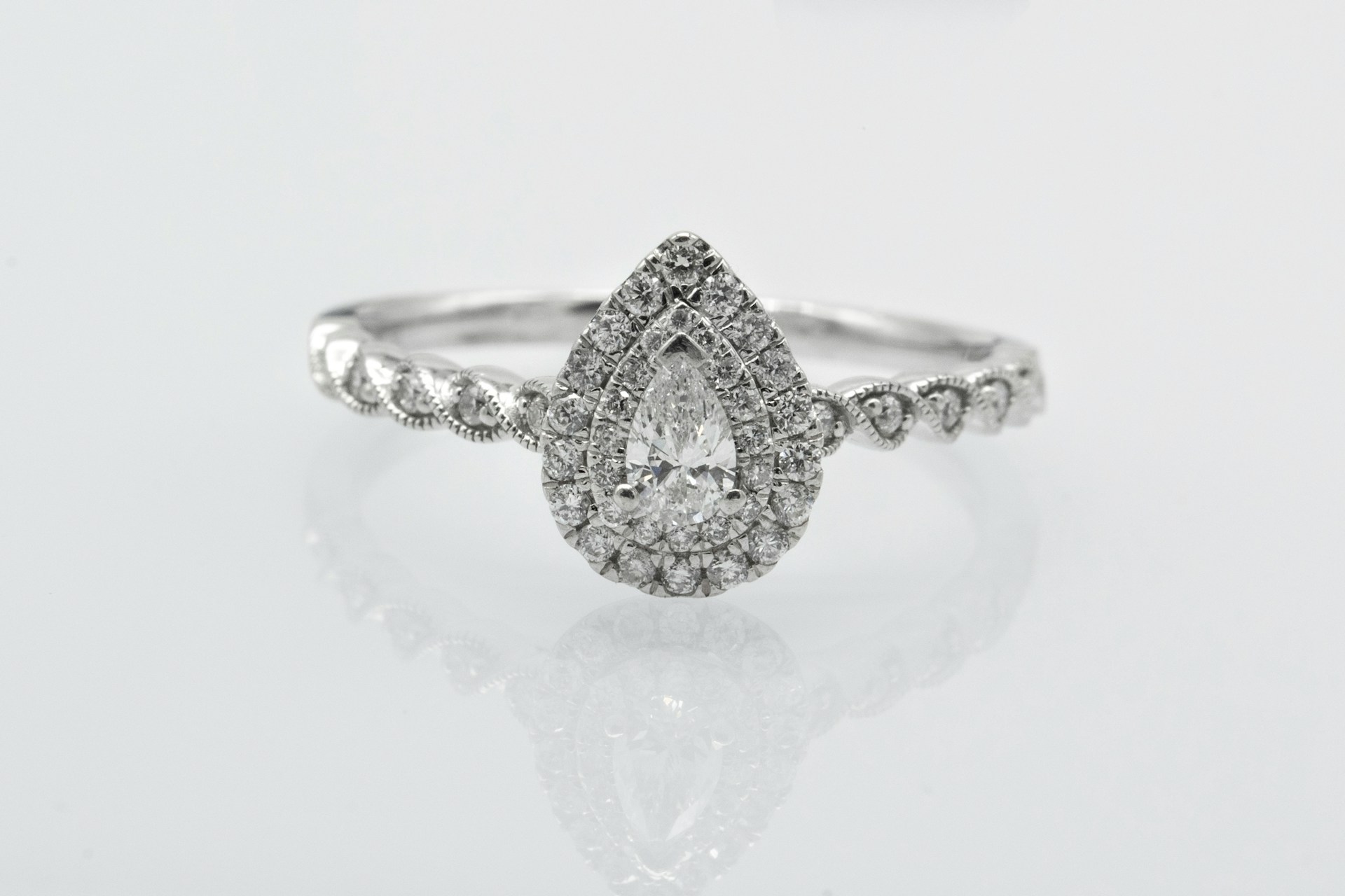 pear shaped halo engagement ring on a grey background