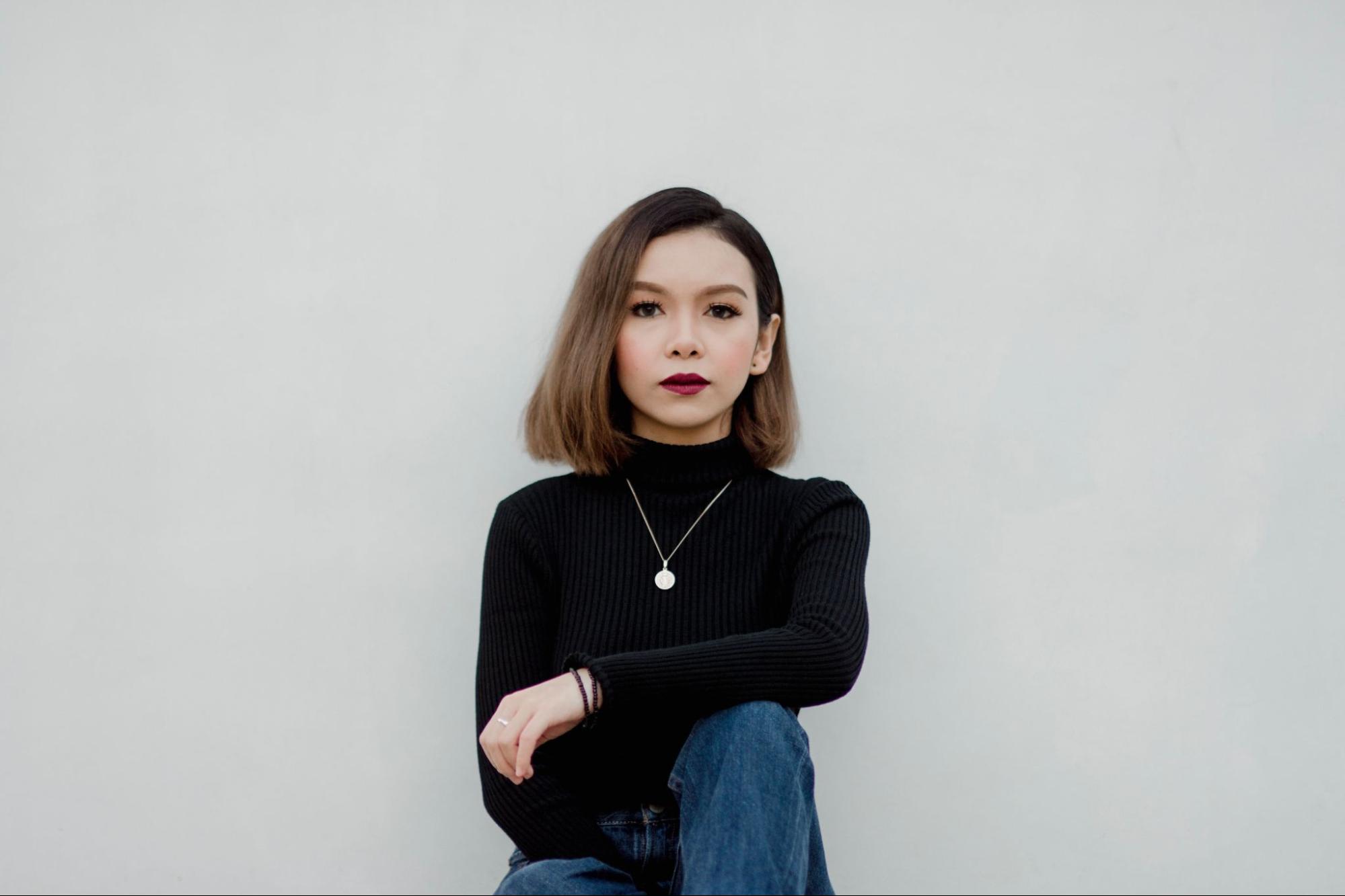 Fashionable lady wearing a necklace on a grey background