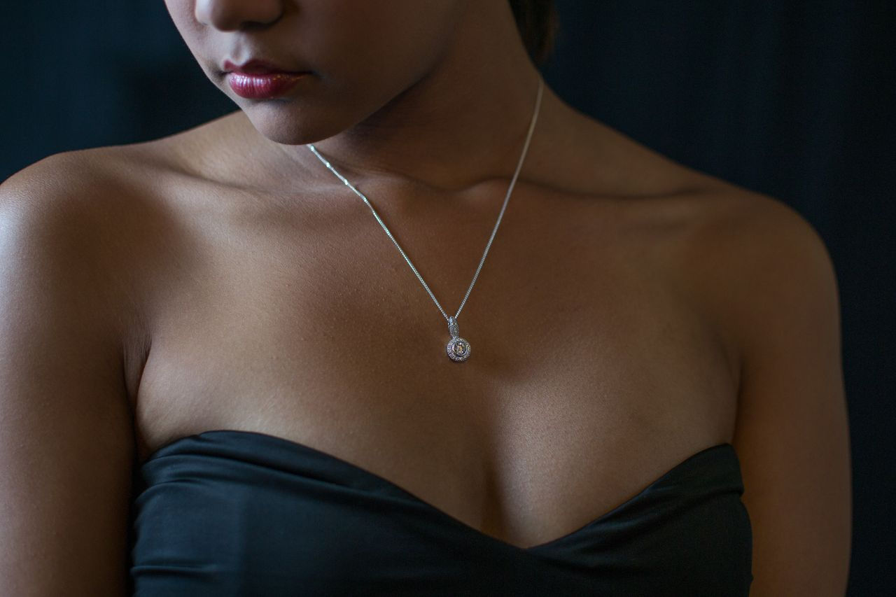 A woman wears a solitaire diamond necklace