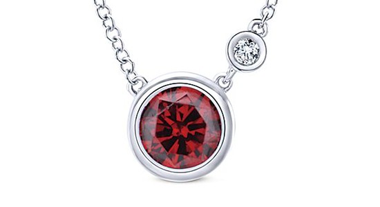 A round cut garnet, bezel set necklace with a diamond accent