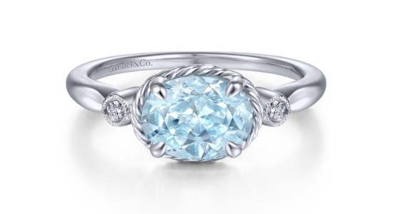 An aquamarine ring set in silver and featuring diamond accents