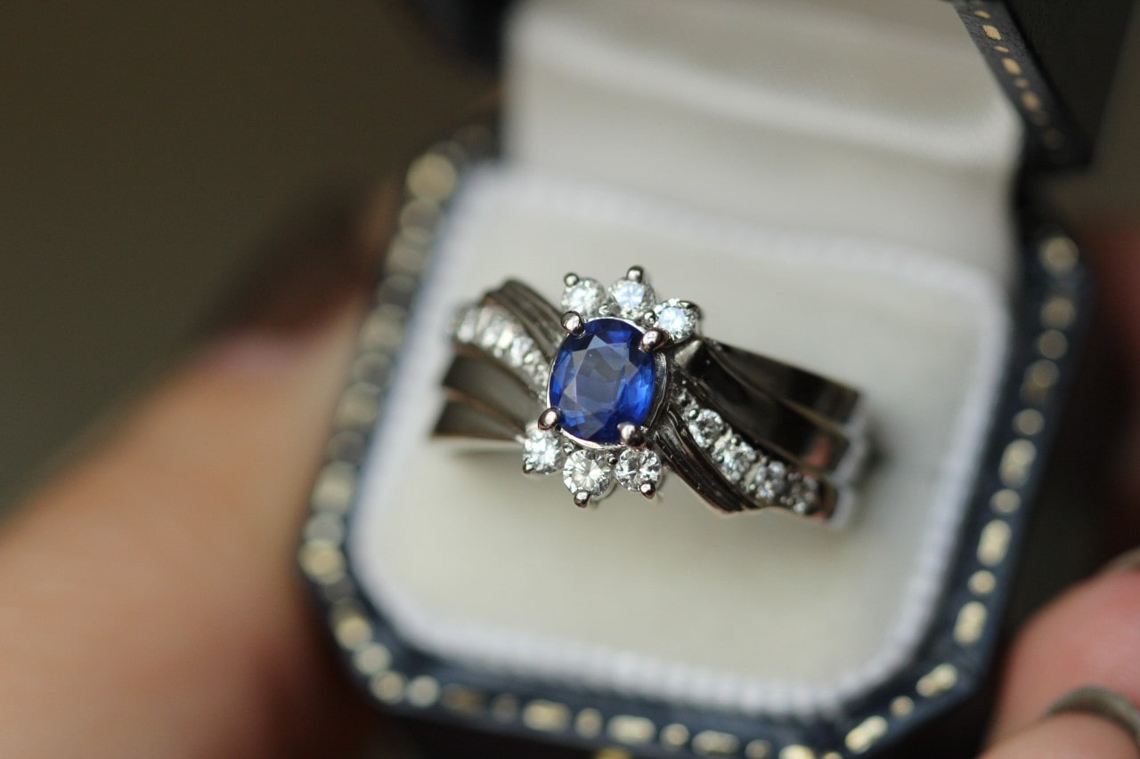 A fashion ring in a box with a sapphire centre stone and diamond accents.