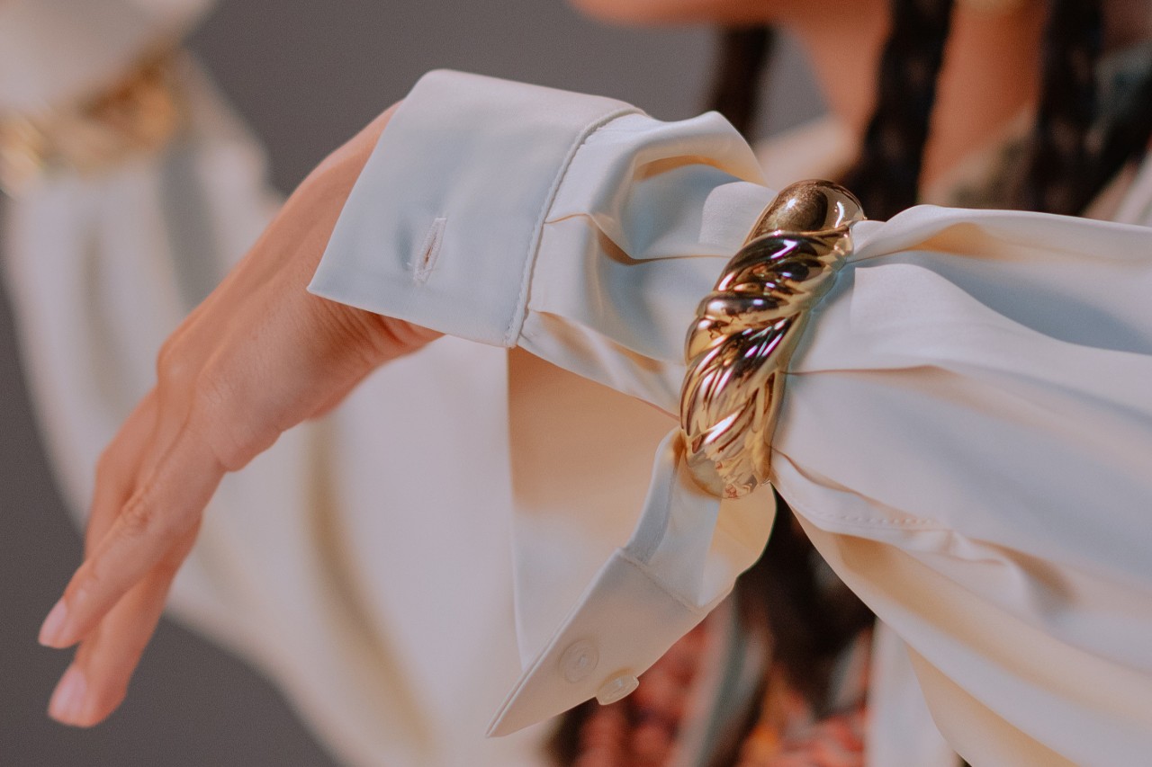 close up image of a woman’s wrist wearing a chunky gold cuff bracelet