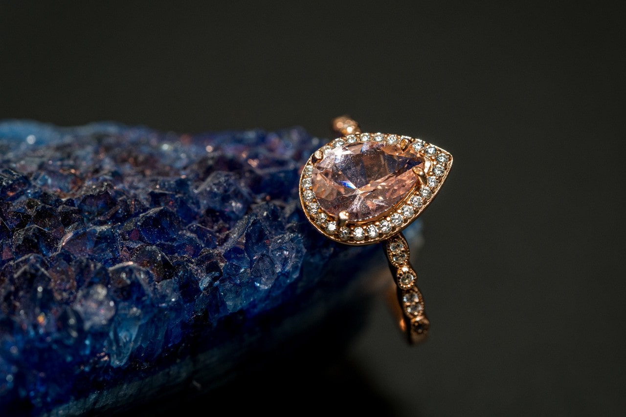 a pear shape fashion ring in rose gold featuring a peach-toned gemstone in a halo setting
