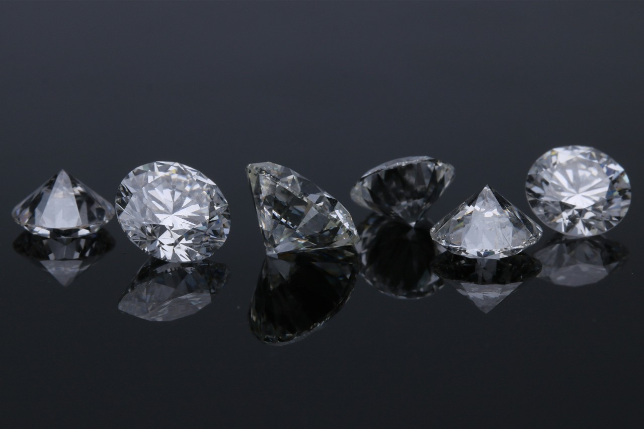 a line of round cut diamonds on a dark, reflective surface