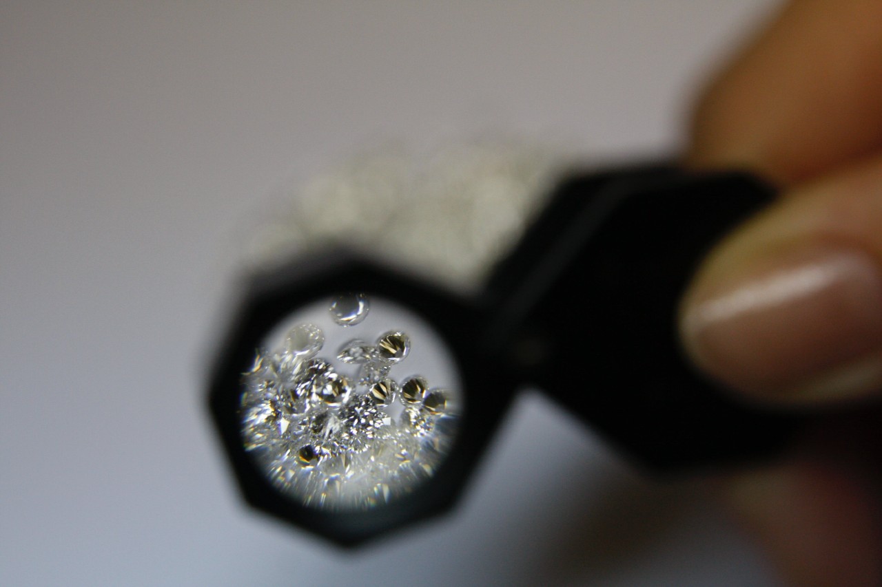 someone looking at diamonds through a small magnifying glass