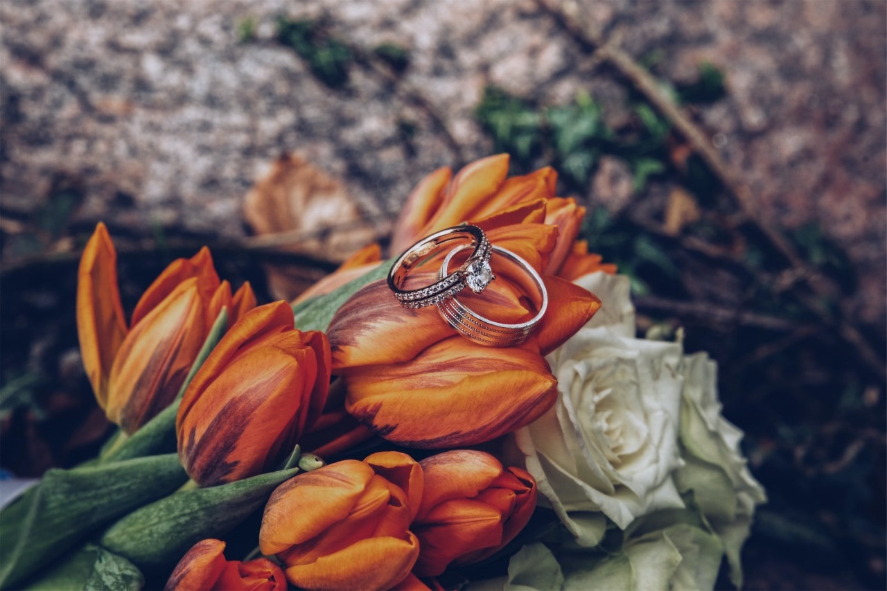 an engagement ring and wedding ring resting on flowers
