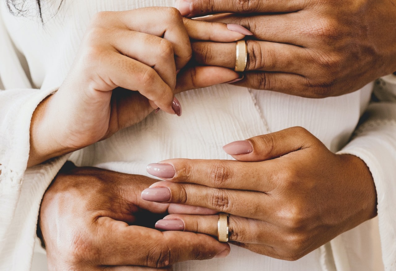 a man and woman simultaneously placing matching wedding bands on each others’ fingers