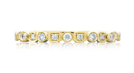 a yellow gold diamond wedding band featuring bezel settings