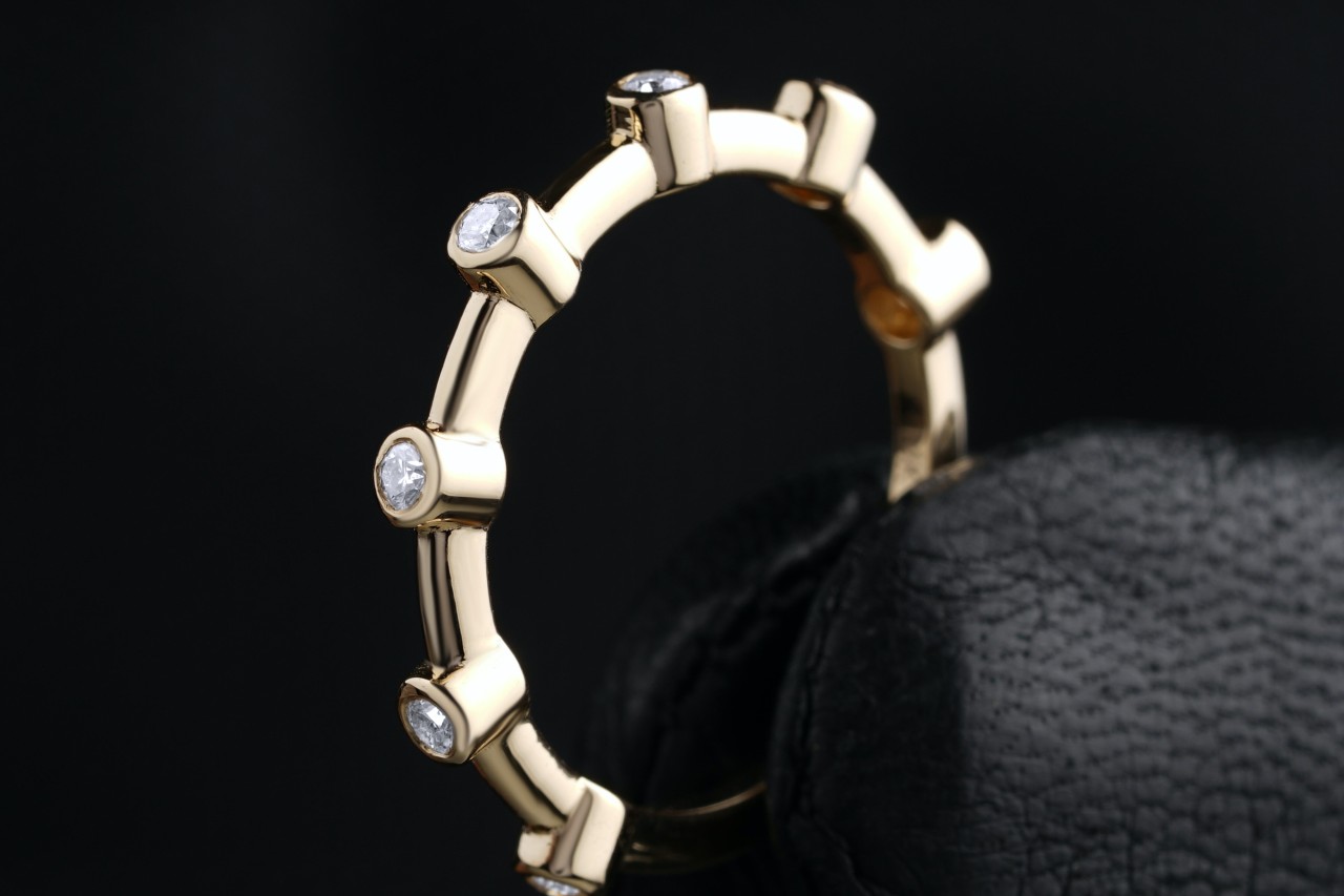 a yellow gold wedding band featuring bezel set round cut diamonds