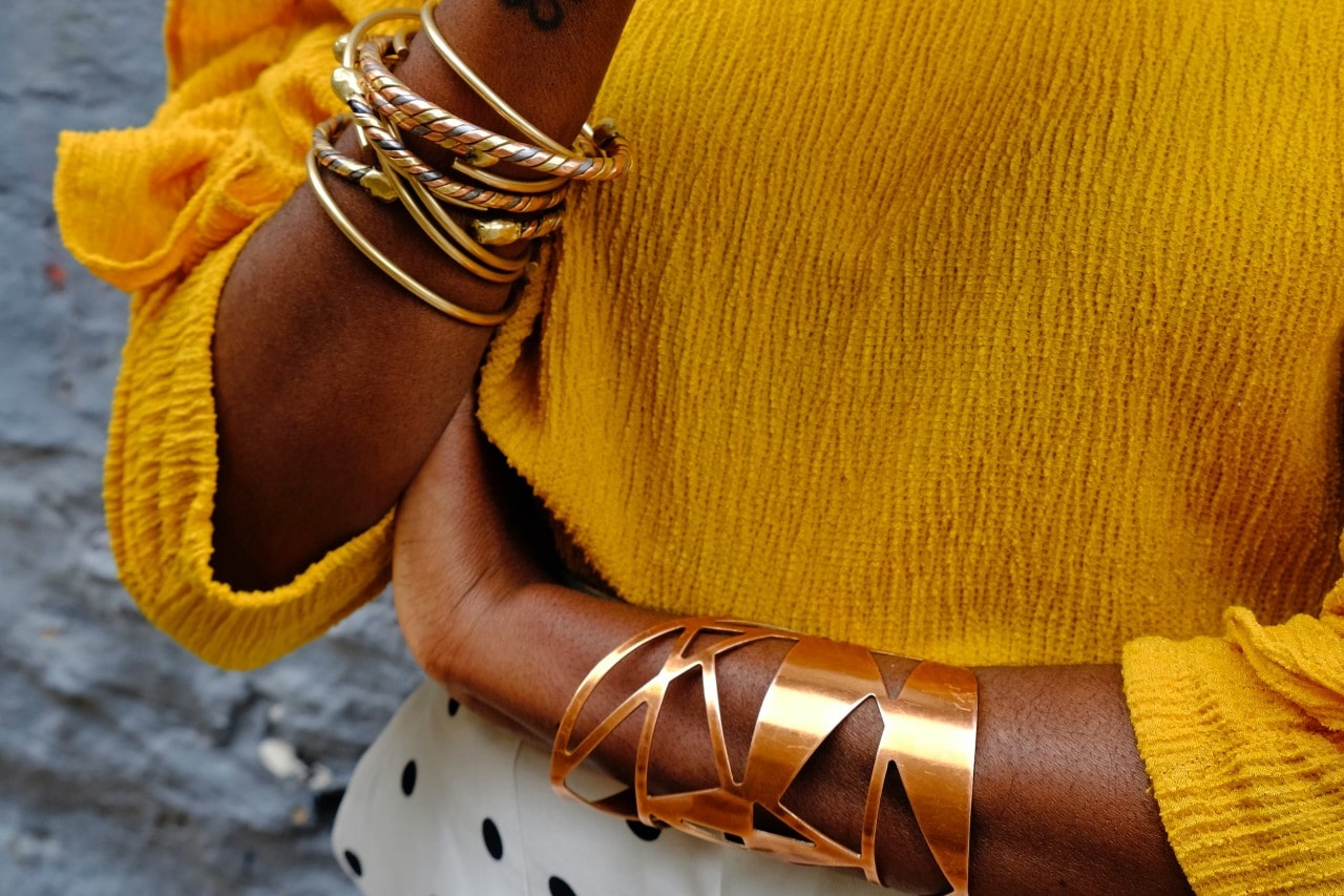 lady’s arms wearing gold bracelets