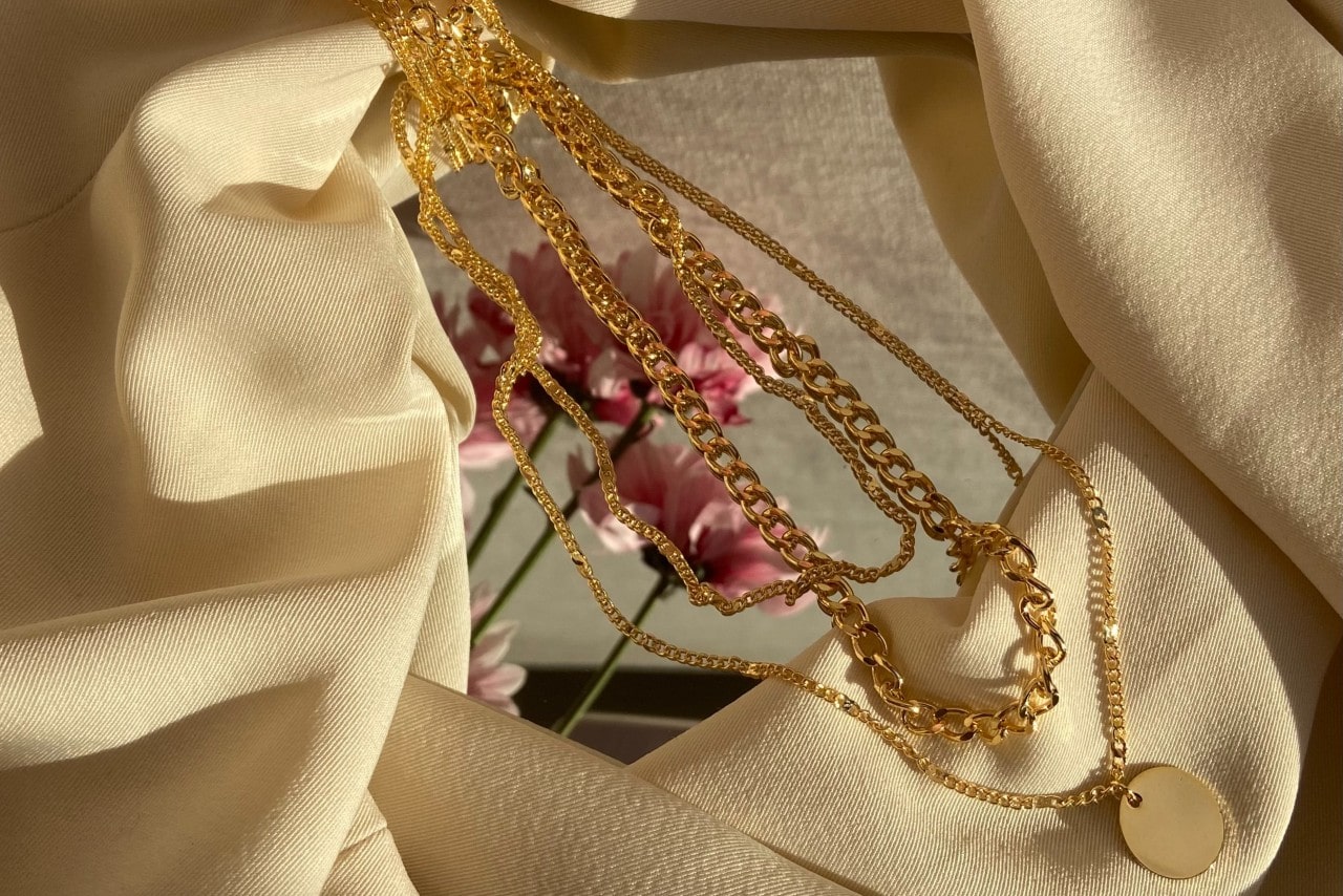 gold chain necklaces sitting on a mirror and cloth