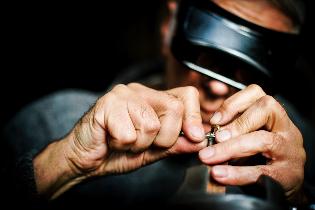 A jeweler focused on a project wearing professional goggles