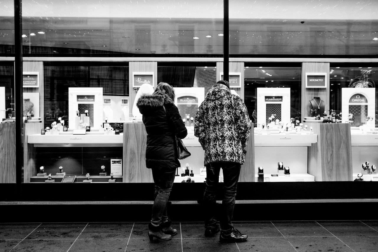 Black and white image of a couple looking in a jewelry store window