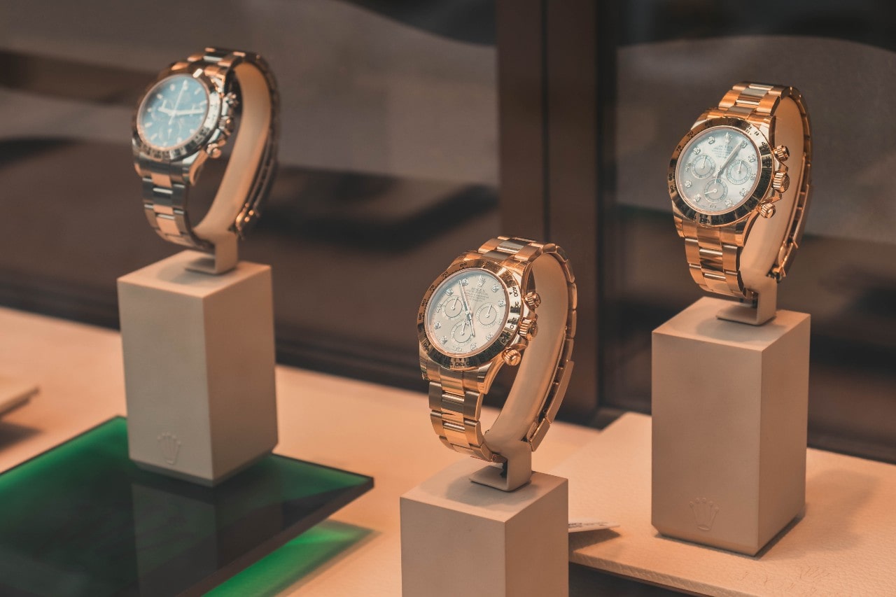 Three luxury watches on stands in a glass case