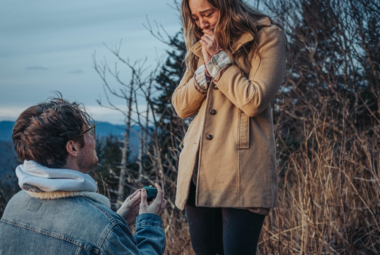 A woman emotionally accepts her boyfriend’s proposal while bundled up on a winter stroll